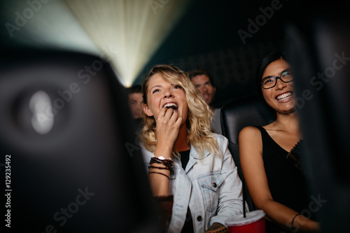 Smiling young women watching movie in theater