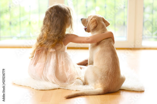 Little girl with golden Labrador dog in room