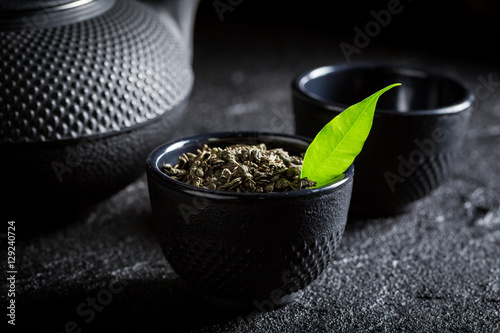 Fresh green tea with teapot and cup on black rock