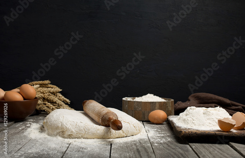 Dough with wooden rolling pin, flour and eggs
