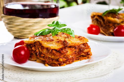 Piece of tasty hot lasagna with red wine..