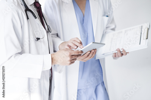 Doctors are talking while watching electronic tablets at a hospital