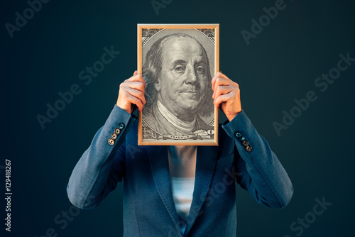 Businesswoman holding Benjamin Franklin 100 USA dollar portrait