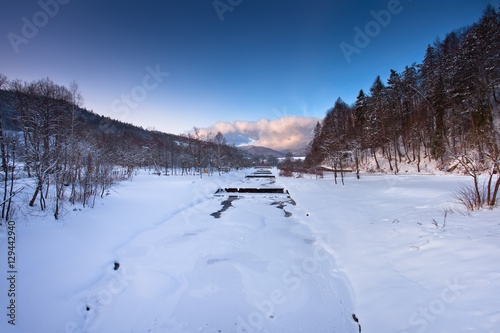 Zachód słońca zimą w górach w mieście górskim Muszyna. Nad potokiem Szczawnik.