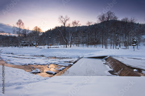 Zachód słońca zimą w górach w mieście górskim Muszyna. Nad potokiem Szczawnik.