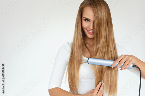 Beautiful Woman Ironing Long Straight Hair With Straightener