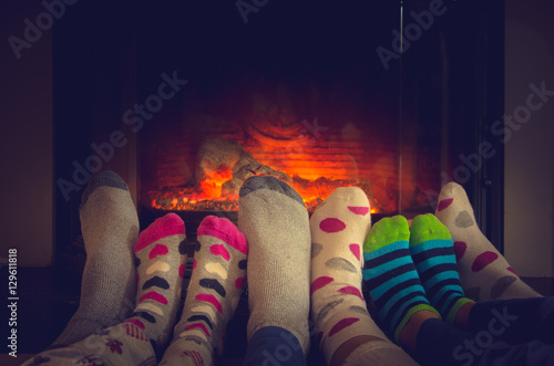 Feet in socks of all the family relaxing and warming by cozy fire