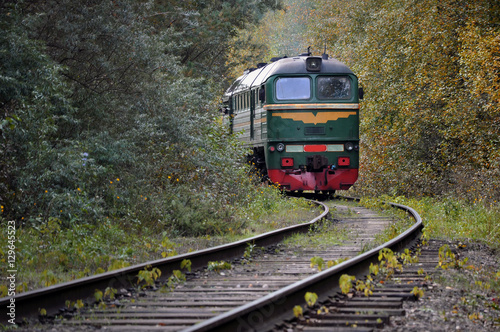 Old train traveling on the tracks in the middle of autumn forest.