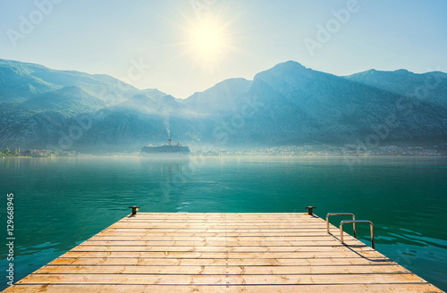 Early misty morning on the pier with sea, Kotor city and mountains on background. Kotor bay. Montenegro