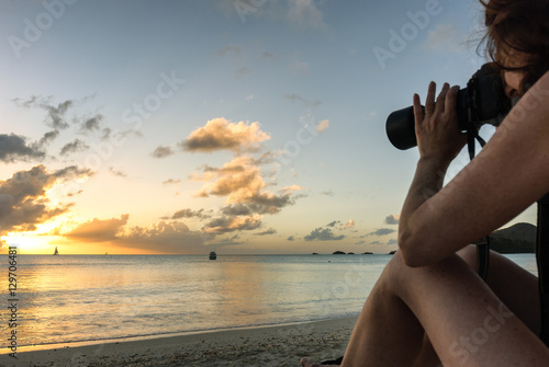 Bikini woman photographer taking picture of tropical beach sunset