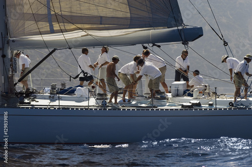 Side view of crew members working on sailboat