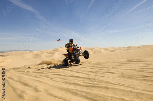 Young quad bike rider doing wheelie in desert