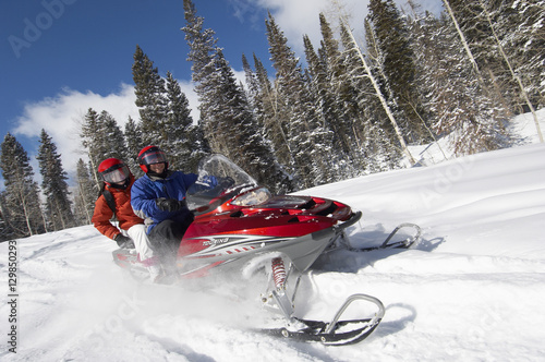 Couple driving snowmobile on snow covered track