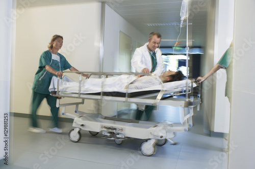 Medical workers moving patient on gurney through hospital corridor