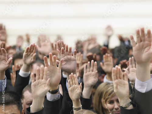 Closeup of business crowd raising hands