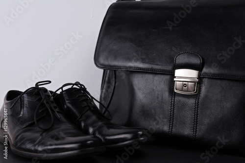 Classic male black shoes and bag to match on black background. Formal business wear.