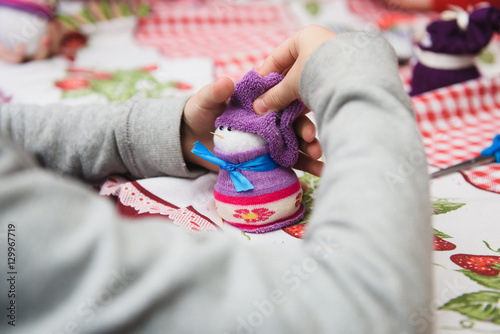 Happy kid doing craft. Small child holding a felt Christmas snowman in hands. Workplace in kindergarten, school or home. Kids Christmas crafts idea. Children winter creativity