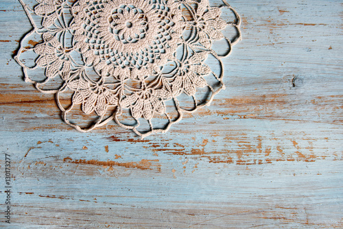 handmade lace on shabby chic, painted, blue wood. Macrame close-up, top view with copy space. Wedding or holiday background.
