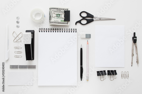 Set of black and white office supplies flat lay. Top view on various stationery on desk: notepads, pencils, scissors, stapler, clip, pins, pen, pencil and bundle of money. Business accessories mocup