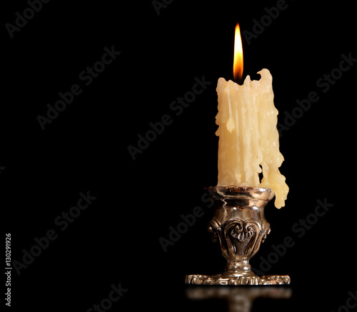 burning old candle vintage Silver bronze candlestick. Isolated Black Background.