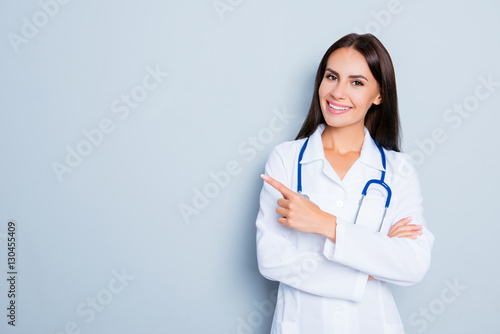 Smiling happy doctor pointing with finger on blue background