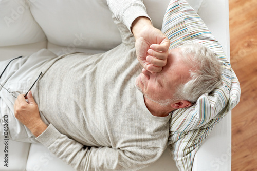 close up of tired senior man lying on sofa at home