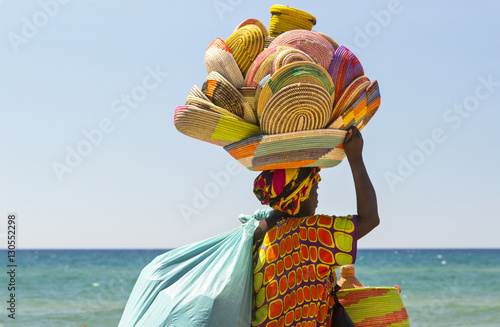 donna africana immigrata che vende cestini in Italia lungo la spiaggia