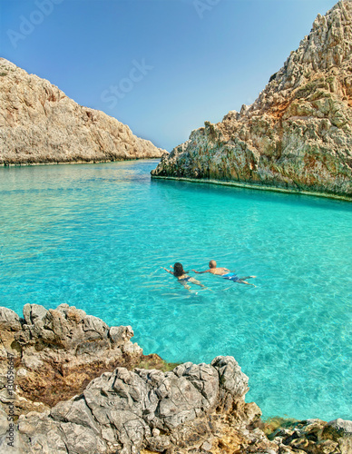 couple swimming in small lagoon surrounded by rocks