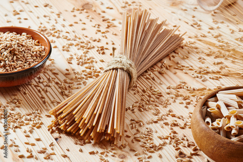 Uncooked whole wheat pasta spaghetti surrounded by wheat