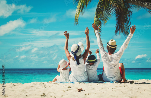 happy family with two kids hands up on beach