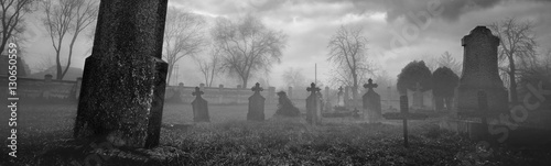 Old creepy graveyard on stormy winter day in black and white