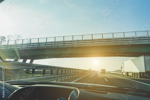 Car window view of trucks speeding in motorway under a overpass