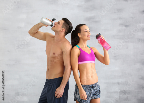 Young sporty couple drinking water in gym