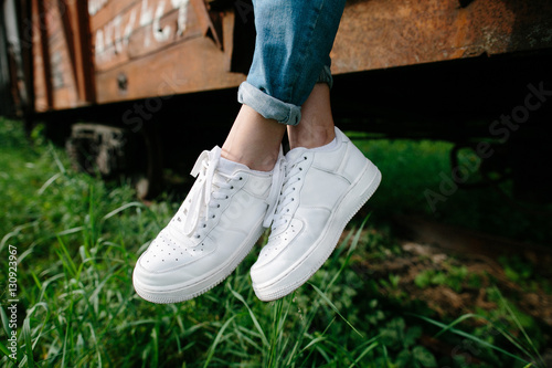 Female sneakers. White female shoes on feet. Sneakers closeup. 