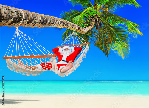 Santa Claus relax in hammock at island palm tropical beach