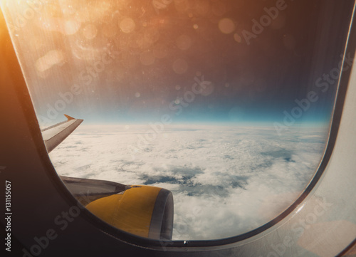 Beautiful wide view from window of aircraft: cloudscape, horizon, airplane wing and orange engine, flare and stylish lens dirt