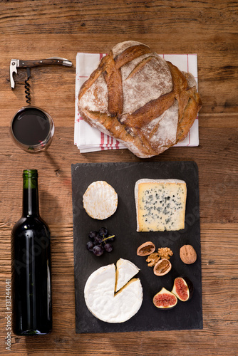 above overhead view flat lay assortment of various cheese with traditional bread fruits glass and bottle of red wine on old wooden table