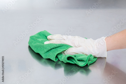 Hand in protective glove with rag cleaning kitchen equipment in the professional kitchen. Stainless steel surface. Early spring cleaning or regular clean up.