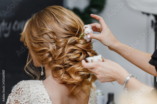 Hair stylist or florist makes the bride a wedding hairstyle with