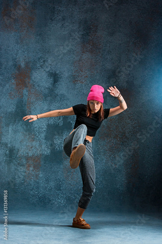 Young girl break dancing on wall background.