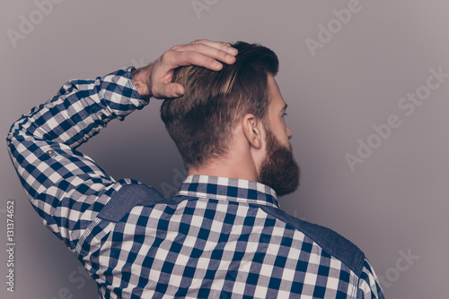 Back-view of stylish handsome young man touch his hair with ha