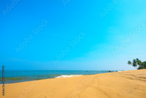 Beautiful beach with sand dunes on tropical island with coconut palm trees and clean sand at clear sunny summer day