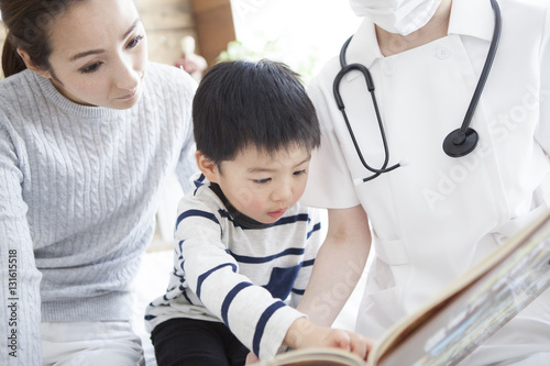 In pediatrics, a nurse is reading a picture book by a boy
