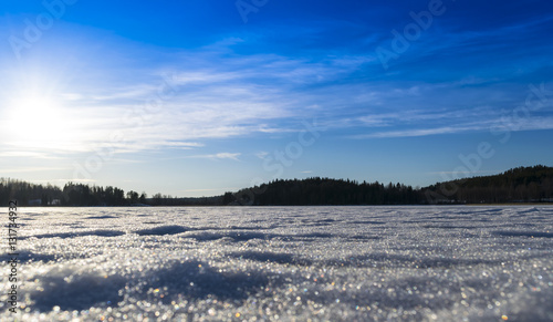 melting ice on frozen lake on a background of rocks and woods