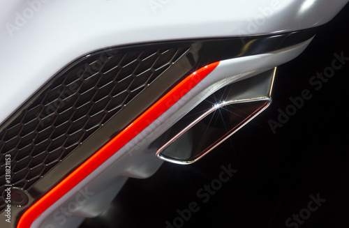 Chrome exhaust pipe of powerful sport car with white bodywork, orange and grey steel and plastic details