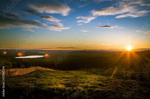 A beautiful landscape with a midnight sun above arctic circle. Dreamy scenery with light flares