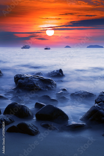 Sunset Ocean Long time Exposure, Blurred Ocean Waves with Stones, Sun and Boats.