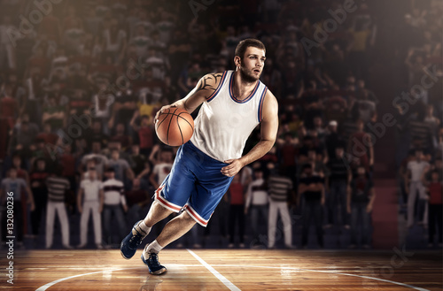 basketball player in light on professional court running with ball