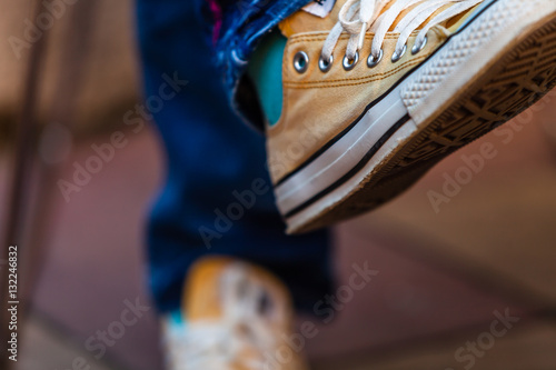 Color picture of woman feet wearing yellow sneakers, detail