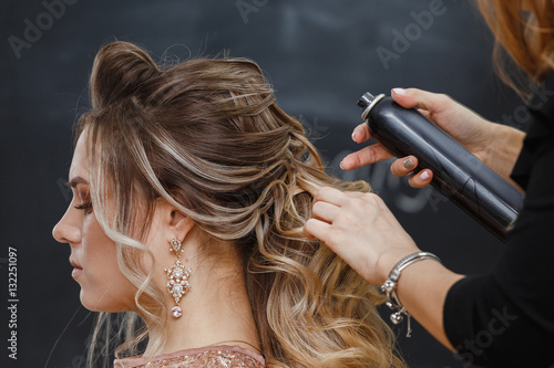 Hairdresser using hairspray on client's hair at salon